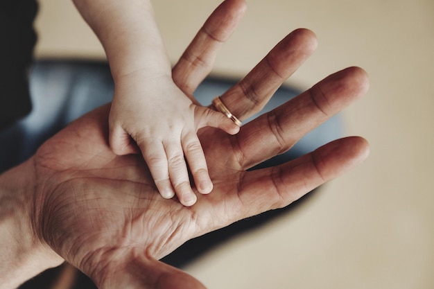 Main de petit enfant sur la paume de papa en gros plan. Le père tient la main du nouveau-né dans sa main. Famille : parents et mains de bébé. Concept de parentalité, de soins parentaux et de fête des pères. Espace de copie pour le site d'images