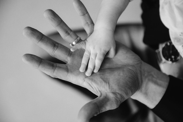 Main de petit enfant sur la paume de papa en gros plan. Le père tient la main du nouveau-né dans sa main. Famille : parents et mains de bébé. Concept de parentalité, de soins parentaux et de fête des pères. Espace de copie pour le site d'images