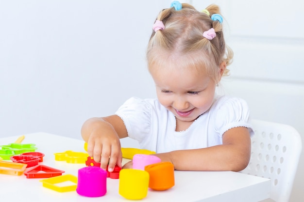 La main d'un petit enfant serre des morceaux de pâte à modeler colorée