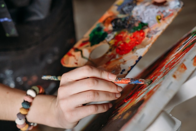 Main avec pinceau de peintre travaillant dans un vrai studio d'art moderne