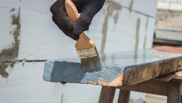 Une main avec un pinceau qui peint un arbre en gris