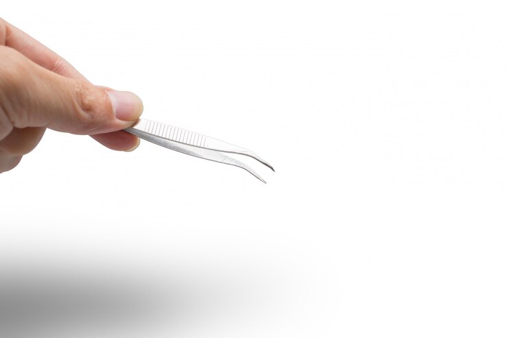 Main avec une pincette médicale petite taille isolée sur blanc avec un tracé de détourage