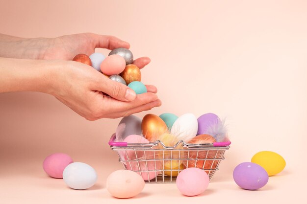 Une main plaçant des œufs de couleurs différentes dans un mini-chariot à panier Concept livraison achat à domicile