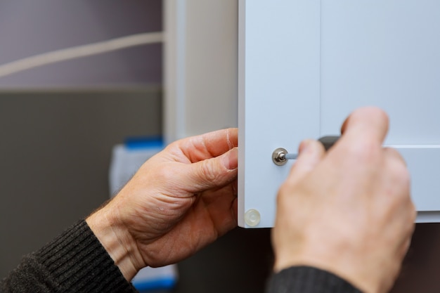 Main sur la poignée d&#39;installation porte dans l&#39;armoire de cuisine avec un tournevis