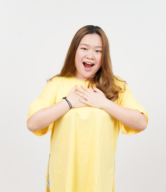 Main sur la poitrine geste reconnaissant de belle femme asiatique portant un t-shirt jaune isolé sur blanc