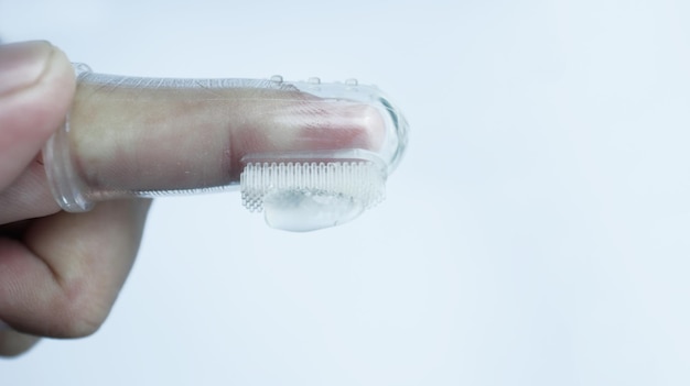 Une main portant une brosse à dents pour bébé ou une brosse à dents pour bébé aidant les premières dents à nettoyer isolées sur blanc un espace négatif
