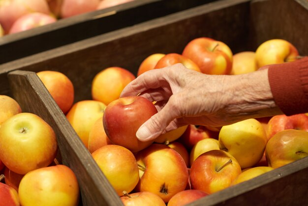 Main prenant des pommes dans un supermarché