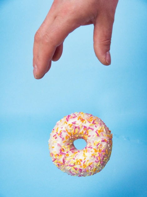 La main prend un délicieux beignet sur un fond bleu