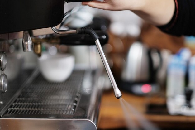 Main près de la machine à café. Libère de la vapeur. Fermer.