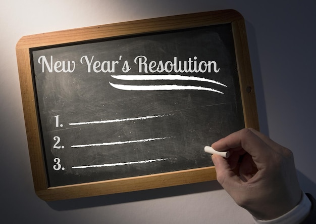 Main qui écrit des objectifs de résolution du nouvel an sur ardoise