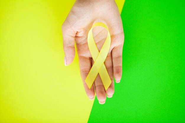 La main avec un ruban jaune symbolise la préoccupation pour le cancer