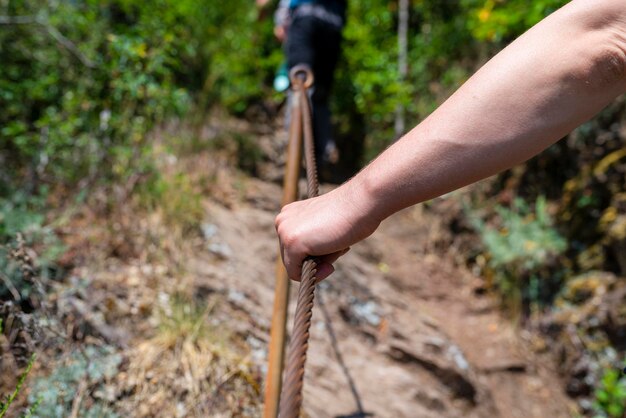 Photo une main saisit fermement la ligne métallique dans les vignobles sur un sentier escarpé d'ardoise