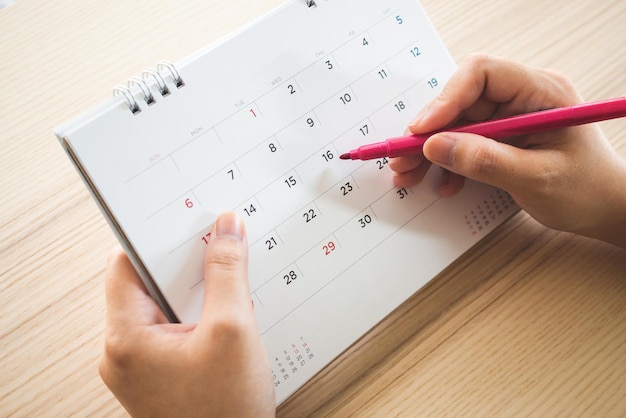 La main avec un stylo écrit sur la page de calendrier libre