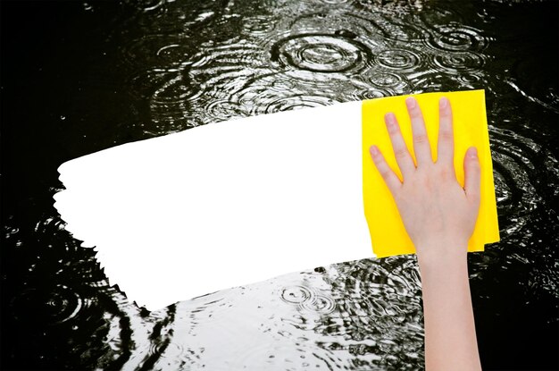 La main supprime la flaque de pluie par un chiffon jaune