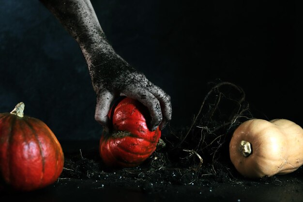 Photo une main tachée de terre ramasse un fond sombre de citrouille mûre joyeux halloween