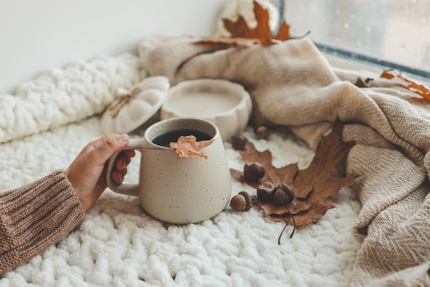 La main avec une tasse de thé bon matin concept humeur d'automne