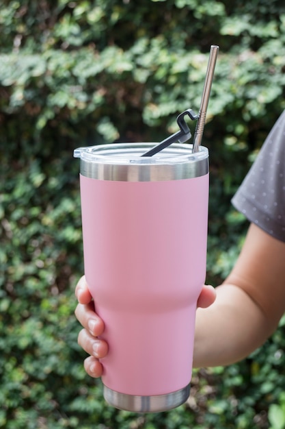 Main sur une tasse thermos avec paille en métal