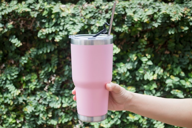 Main sur une tasse thermos avec paille en métal