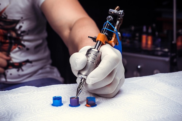 Main D'un Tatoueur Avec Une Machine à Tatouer./main D'un Tatoueur  Professionnel Et D'un Pistolet à Tatouer.