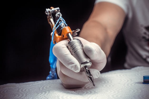 Main d'un tatoueur professionnel avec une machine à tatouer