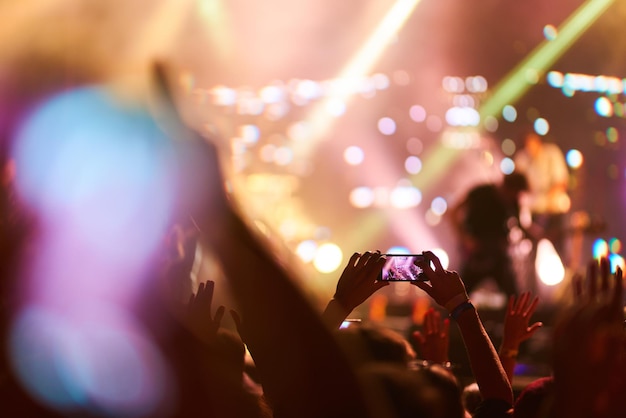 La main avec un téléphone enregistre un festival de musique en direct Les gens prennent des photos avec le téléphone pendant le concert