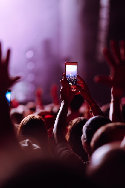 Main avec un téléphone enregistre un festival de musique en direct Personnes prenant des photos avec un smartphone