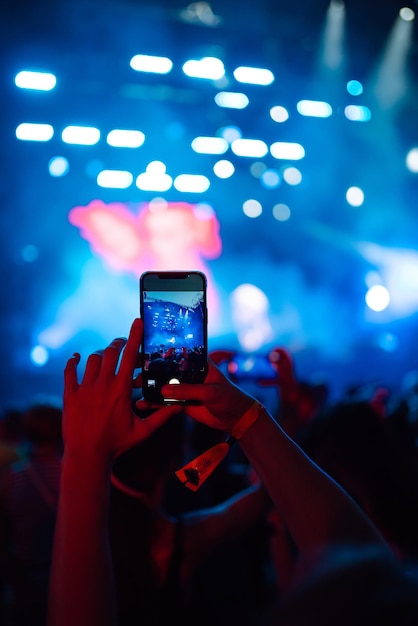 Main avec un téléphone enregistre un festival de musique en direct Personnes prenant des photos avec un smartphone