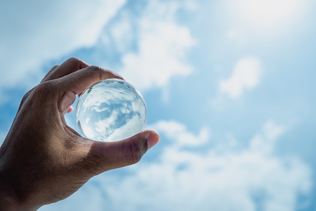 La main tenait une boule de verre et brillait au ciel bleu.