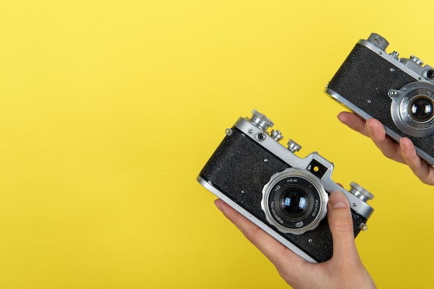 une main tenant un appareil photo vintage sur fond jaune avec un espace pour un texte