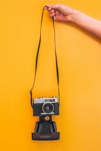 Main tenant un appareil photo Vintage isolé au mur orange