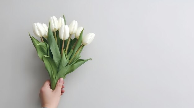 La main tenant un beau bouquet de fleurs de tulipes isolée sur un fond de mur clair