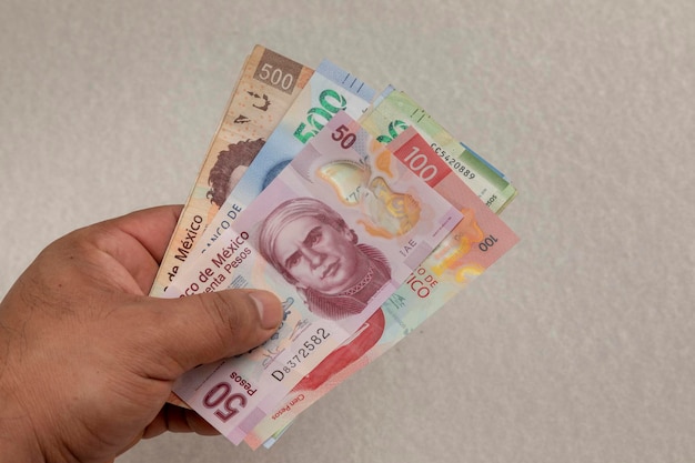 Main tenant des billets de peso mexicain de différentes dénominations