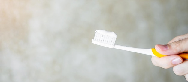 Main tenant des brosses à dents avec du dentifrice dans la salle de bain. Mode de vie, routine quotidienne, journée mondiale de la santé bucco-dentaire et concept de journée dentaire gratuite