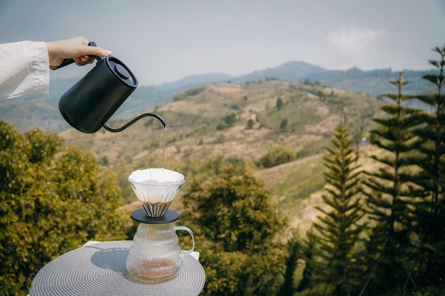 Main tenant le café versant avec vue sur les montagnes floues le matin, concept d'espace de copie