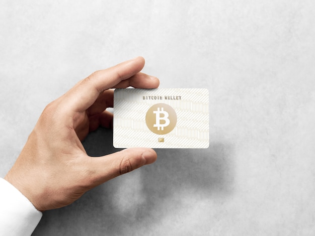 Main tenant la carte bitcoin avec logo doré en relief