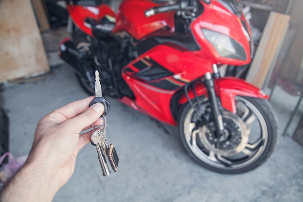 Main tenant une clé dans le garage, sur la moto.