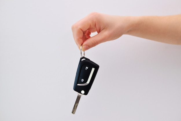 Une main tenant une clé de voiture sur un fond blanc.