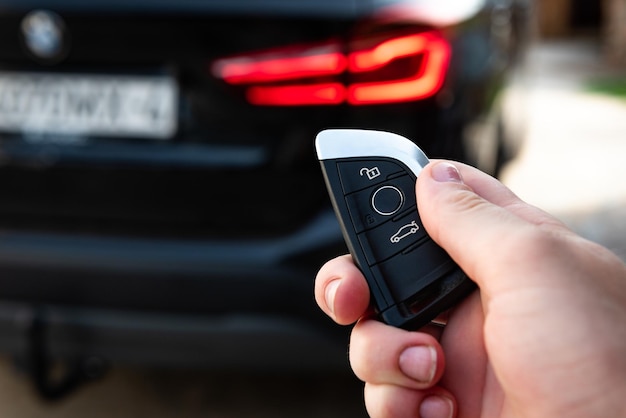 Main tenant une clé de voiture avec télécommande et appuyant sur un bouton, il déverrouille la porte.