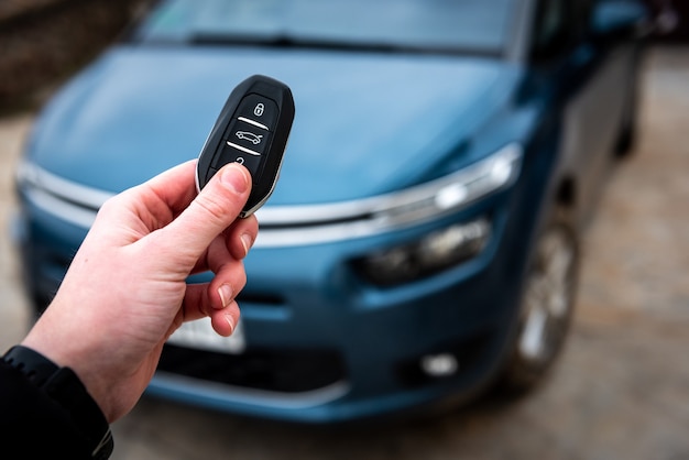 Photo main tenant une clé de voiture avec télécommande et en appuyant sur un bouton