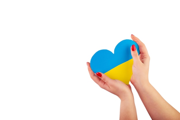 Main tenant un coeur fabriqué à partir du drapeau de l'Ukraine bleu jaune sur un fond blanc isolé