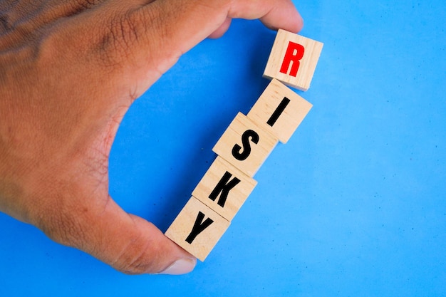 main tenant un cube en bois avec le mot risqué Concept de gestion des risques ou d'évaluation et de décision