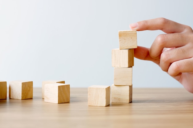 Main tenant des cubes en bois vides sur une table en bois sur blanc