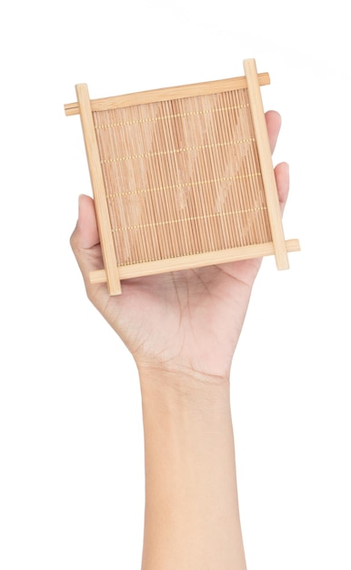 Main tenant un dessous de verre en bambou carré isolé sur fond blanc.