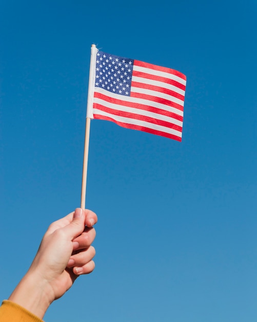 Photo main tenant le drapeau américain sur ciel bleu