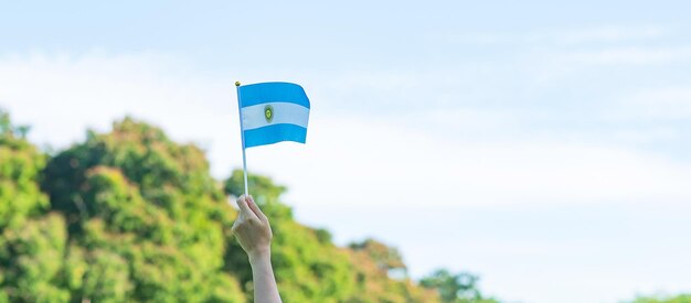 Main tenant le drapeau de l'Argentine sur fond de nature 9 juillet du jour de l'indépendance 25 mai du jour de la révolution et concepts de célébration heureuse