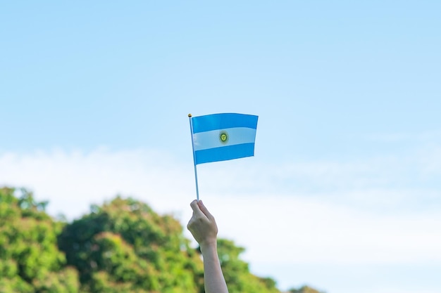 Main tenant le drapeau de l'Argentine sur fond de nature 9 juillet du jour de l'indépendance 25 mai du jour de la révolution et concepts de célébration heureuse