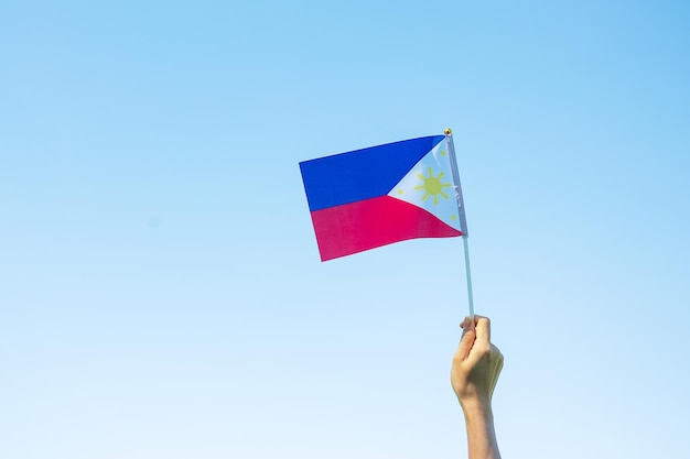 Main tenant le drapeau des Philippines sur fond de nature 12 juin de la fête de l'indépendance et des concepts de célébration heureuse