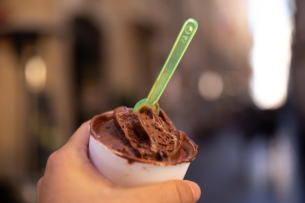 Main tenant une glace au chocolat sur une baignoire dans les rues de Roma.