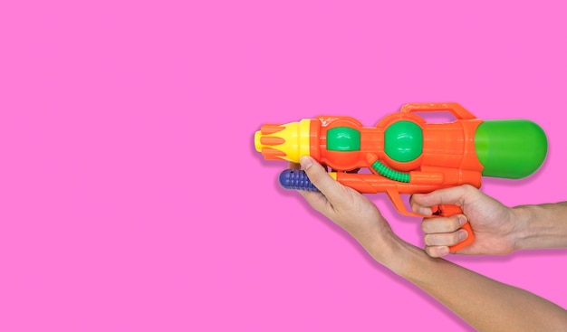Main tenant le jouet de l'eau de pistolet sur fond rose. Espace libre pour le texte