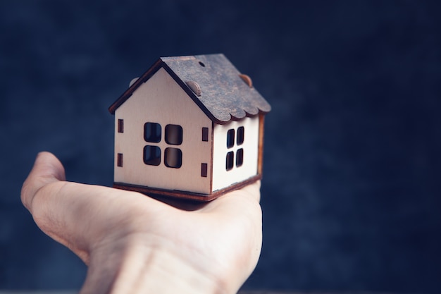 Main tenant une maison sur fond noir